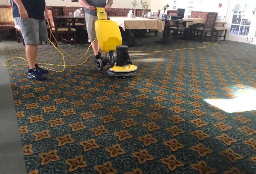 Technicians cleaning commercial carpet with a rotary machine